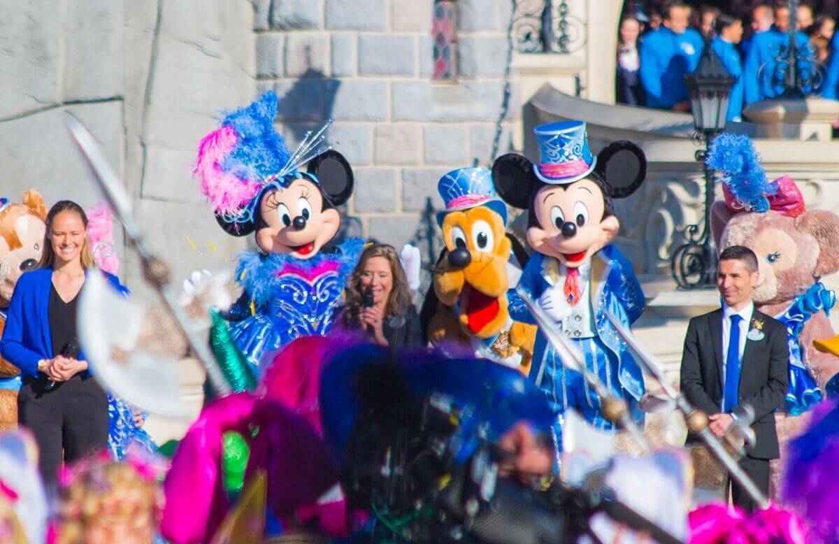 Rede von Catherine Powell, bei der Minnie Mouse, Pluto und Mickey hinter ihr stehen