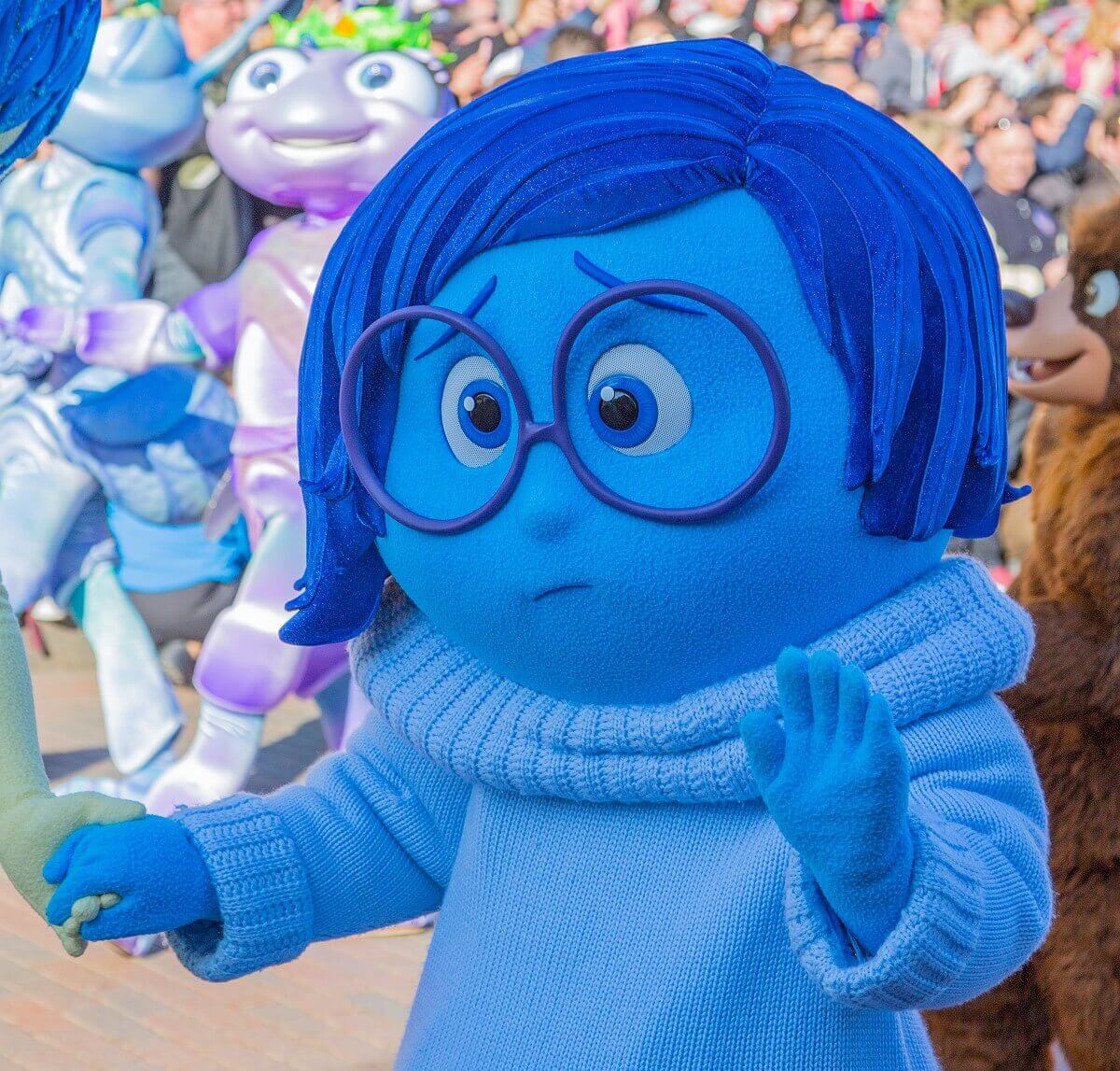 Die Disney Figur Trauer / Sadness ist bei der großen Geburtstagsshow von Disneyland Paris mit dabei und winkt den Zuschauern zaghaft zu