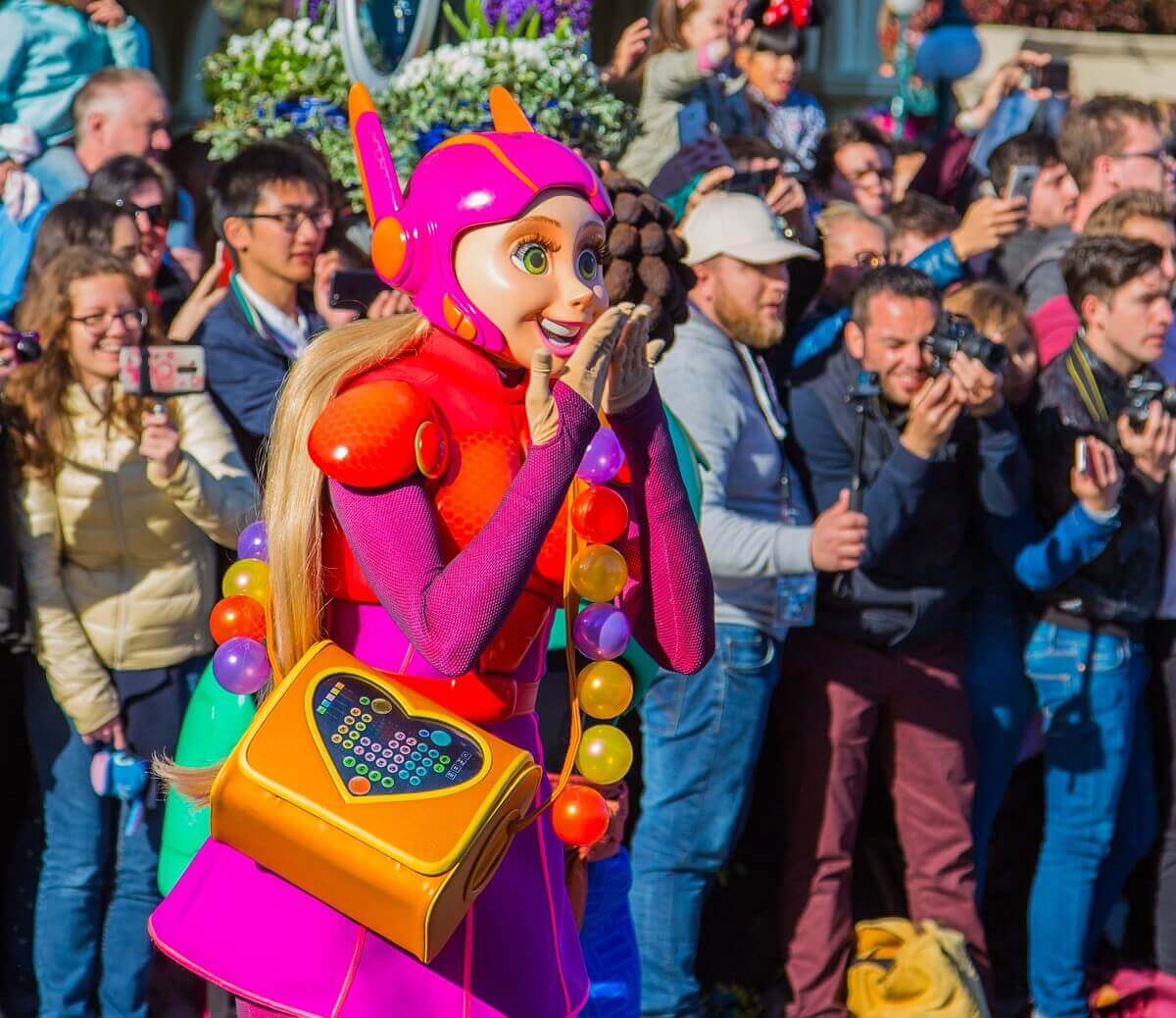 Honey Lemon aus Baymax hat die Hände vor den Mund geschlagen, hinter ihr die Zuschauer der Geburtstagsparade