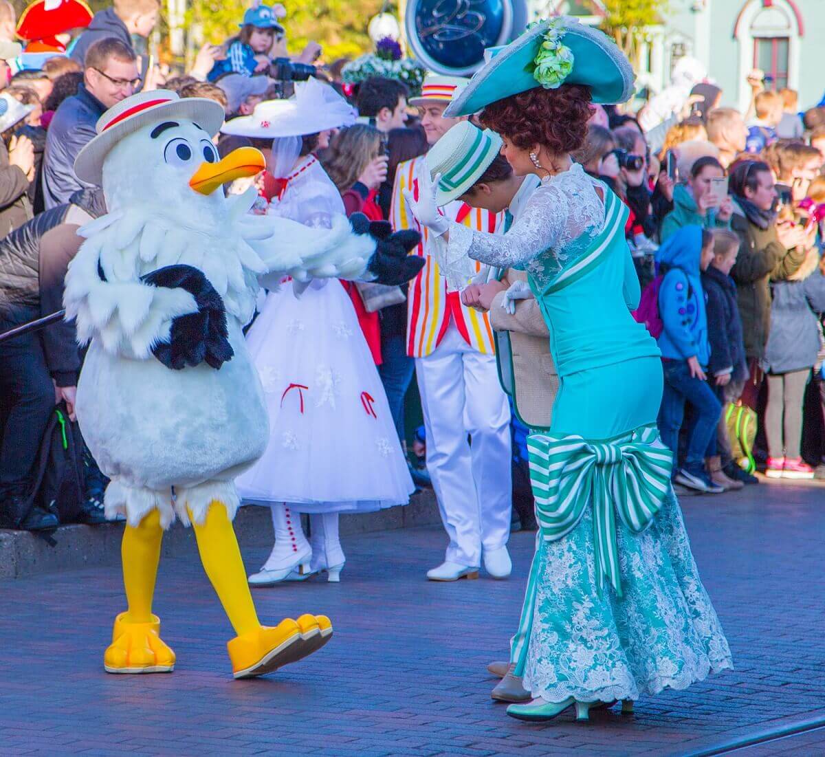 Eine der Möwen aus Frozen grüßt zwei Tänzer bei der Parade, im Hintergrund sind Mary Poppins und Bert zu erkennen