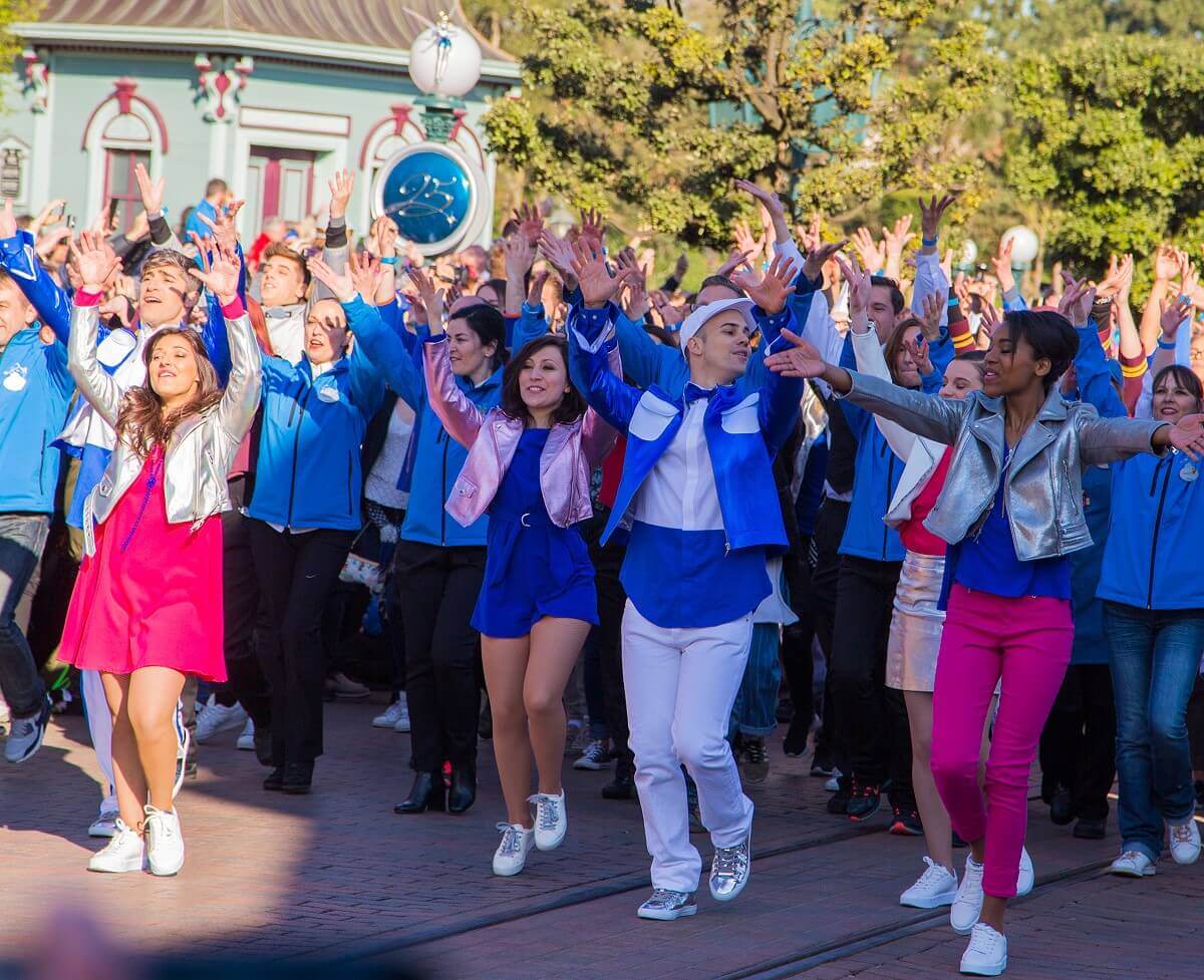 Cast Member von Disneyland Paris tanzen bei der Jubiläums Parade im Stil eines Flashmobs mit