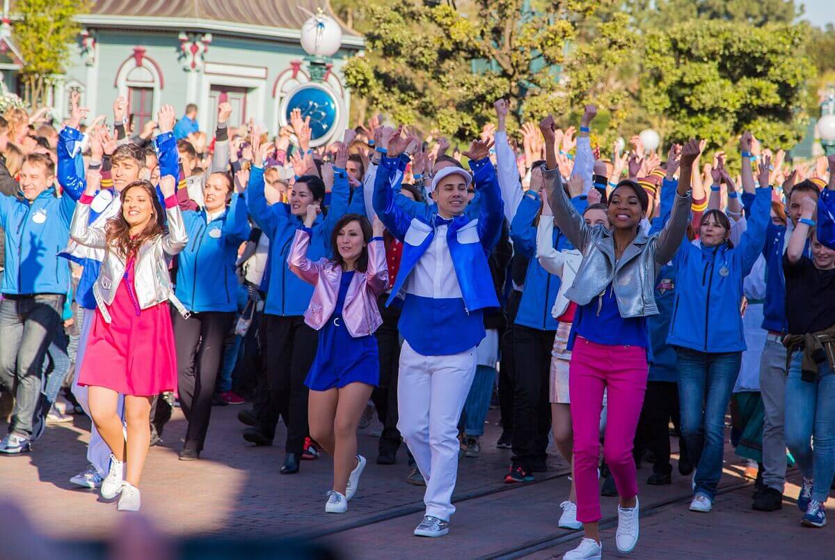 Cat Member von Disneyland Paris tanzen gemeinsam mit erhoben Armen über die Main Street, U.S.A.
