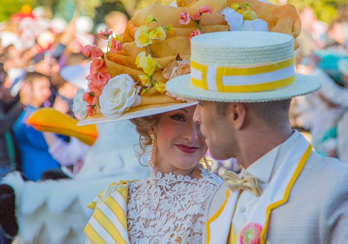 Nahaufnahme eines Tänzerpaares in Kleidung, die an den Film Mary Poppins denken lasst. sie trägt einen ausladenden Hut mit Blumenschmuck, er einen beigarbenen Strohhut