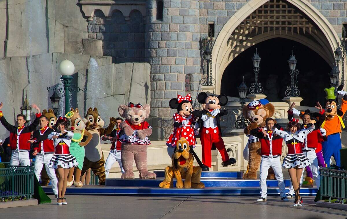 Mickey Mouse, Minnie Mouse, Duffy, Shellie May, Goofy, Pluto und diverse Tänzer auf einer kleinen Bühne am Fuße des Sleeping Beauty Castle