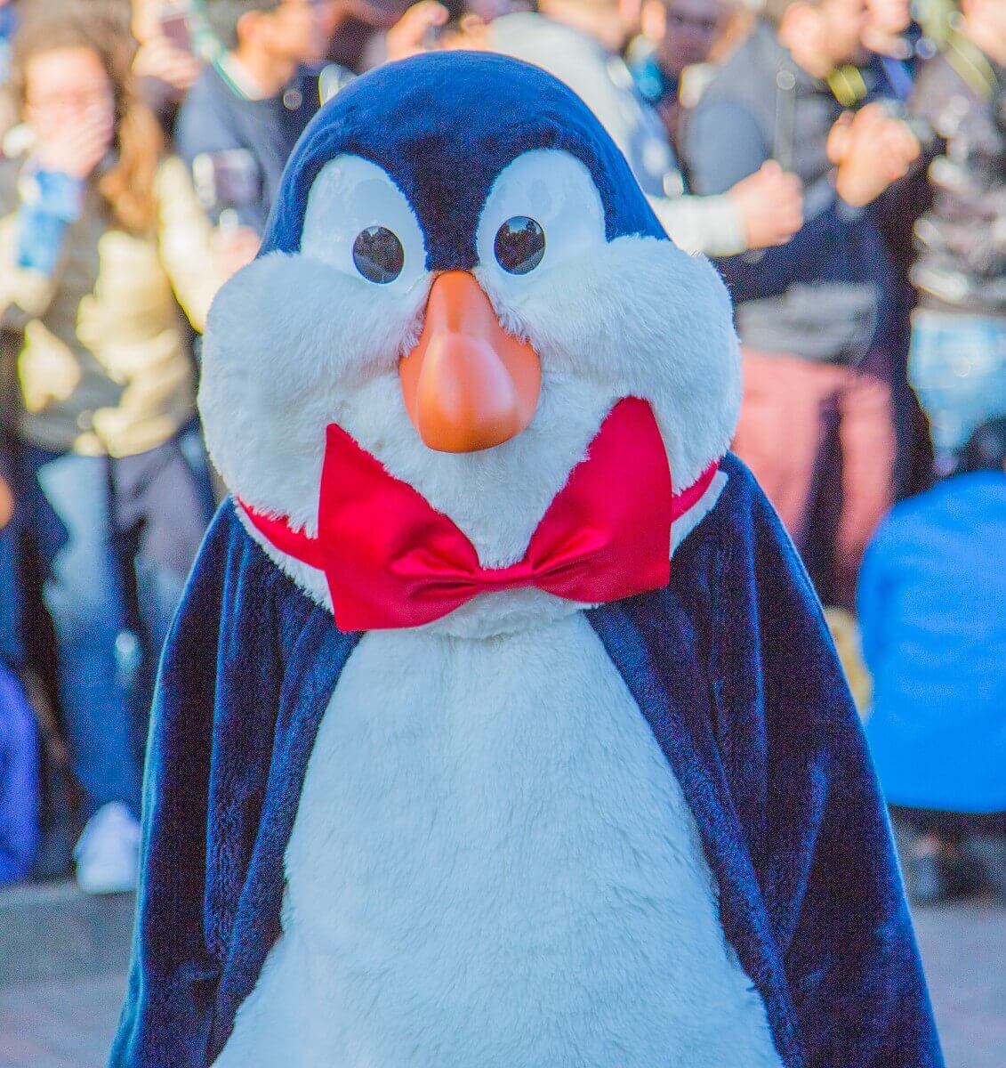Nahaufnahme eines der Pinguine aus dem Film Mary Poppins. Er hat die Flügel angelegt und trägt eine rote Fliege um den Hals