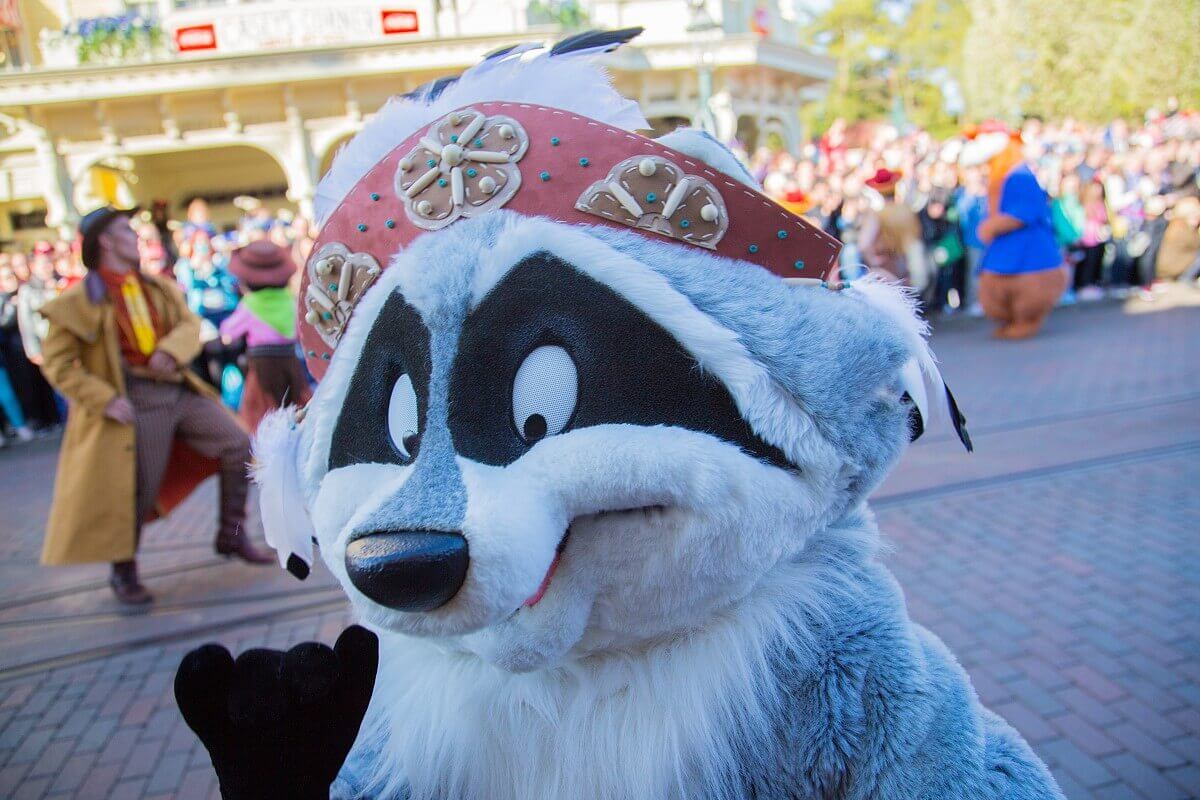 Nahaufnahme von Meeko mit Indianerkopfschmuck, der bei der Show zum 25. Geburtstag von Disneyland Paris direkt in die Kamera winkt