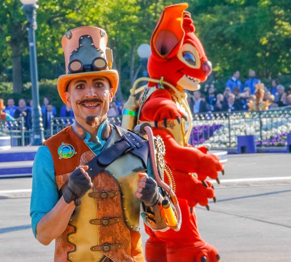 Ein Tänzer im Steampunkkostüm und mit Ziegenbart auf dem Central Plaza, dahinter Alien Leroy