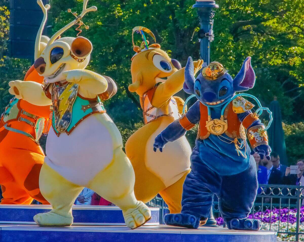 Stitch, Ruben und Sparky tanzen auf der Bühne am Central Plaza. sie alle tragen Kostüme im Steampunk-Look