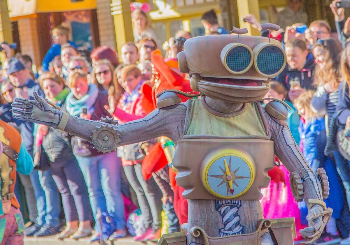 Der Roboter B.E.N läuft mit ausgestrecktem Arm an den Zuschauern auf der Main Street, U.S.A. vorbei, als ob er sie der Reihe nach abklatschen wollte