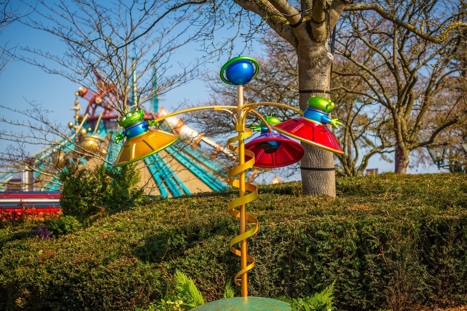 Toy Story Aliens Skulptur mit drei Aliens in fliegenden Untertassen, im Hintergund ist das Gebäude von Space Mountain zu sehen
