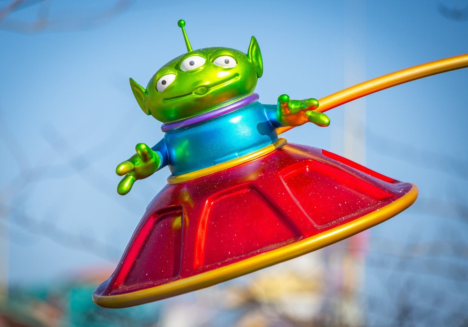 Ein grünes dreiäugiges Toy Story Aliens in einer roten fliegenden Untertasse