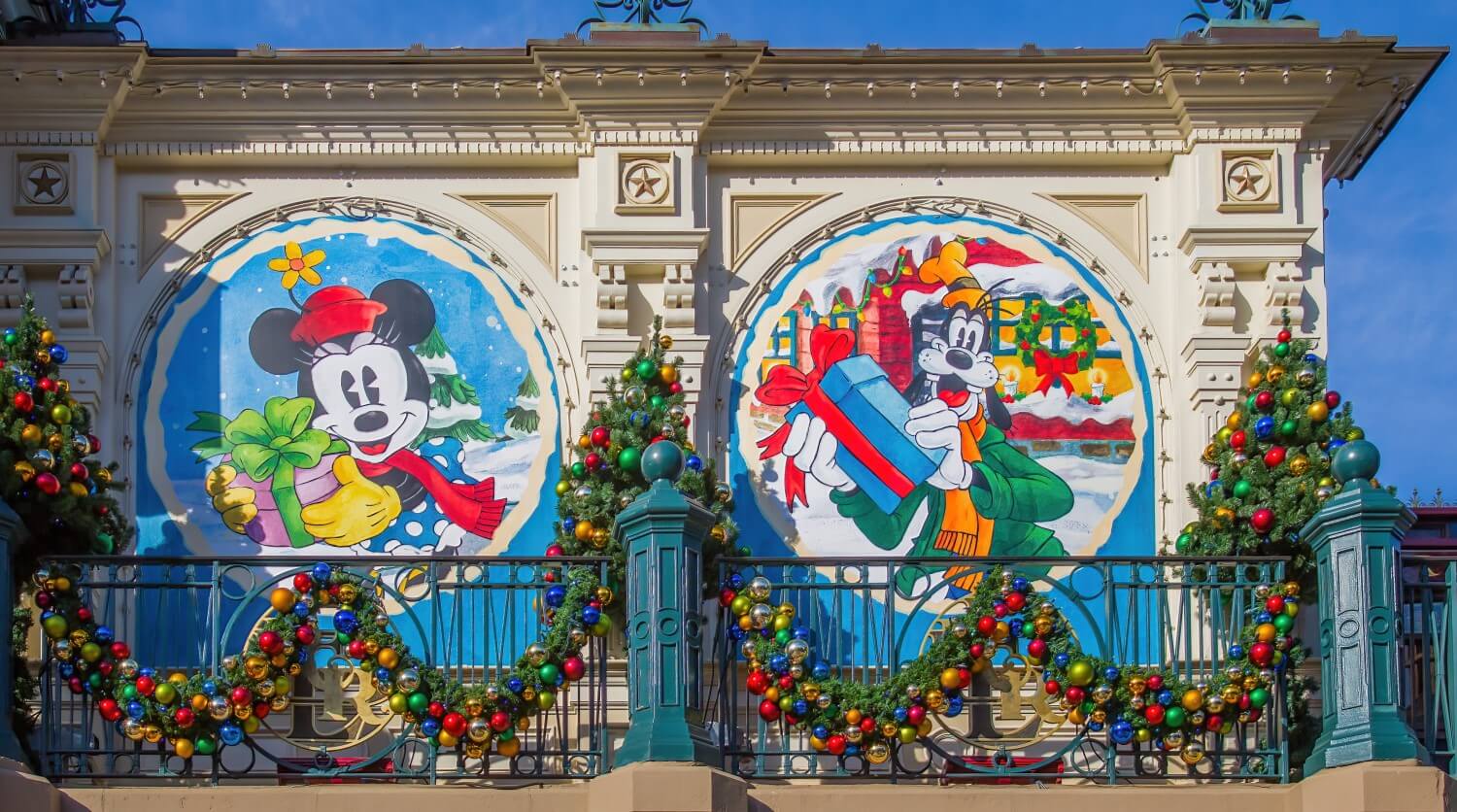 Tafeln vor den Fenstern des Bahnhofs, die weihnachtliche Motive mit Minnie Mouse & Goofy mit Geschenken zeigen