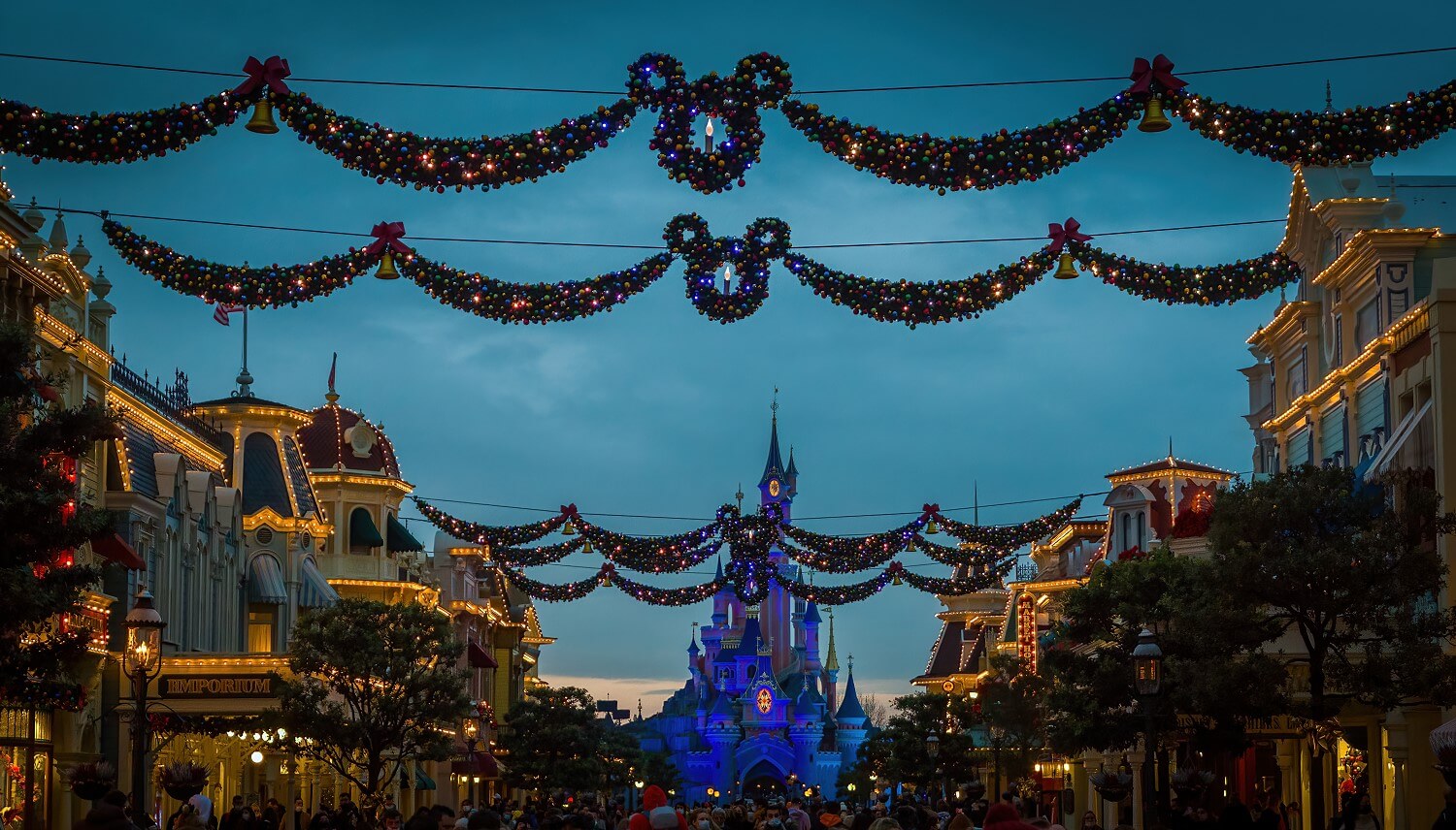 Die abendliche Main Street U.S.A. zur Weihnachtszeit mit über die Straße gespantten, beleuchteten Girlanden