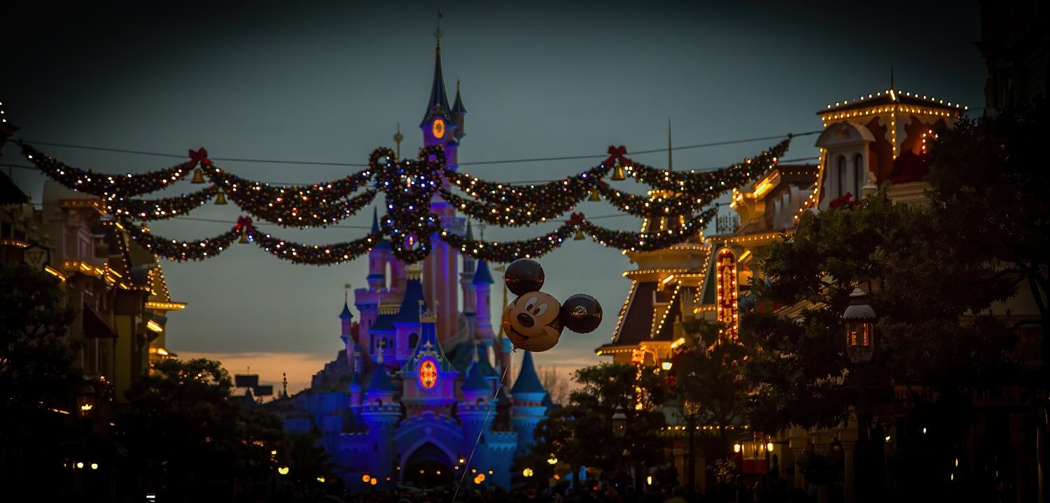 Die abendliche Main Street U.S.A. zur Weihnachtszeit mit über die Straße gespantten, beleuchteten Girlanden