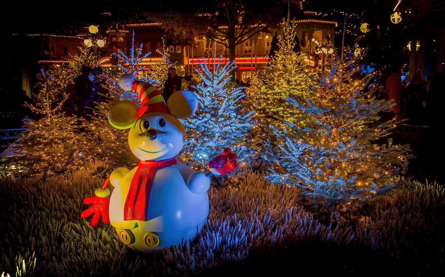 Schneemann im Mickey Mouse Look vor einem kleinen Wäldchen verschneiter Bäumchen