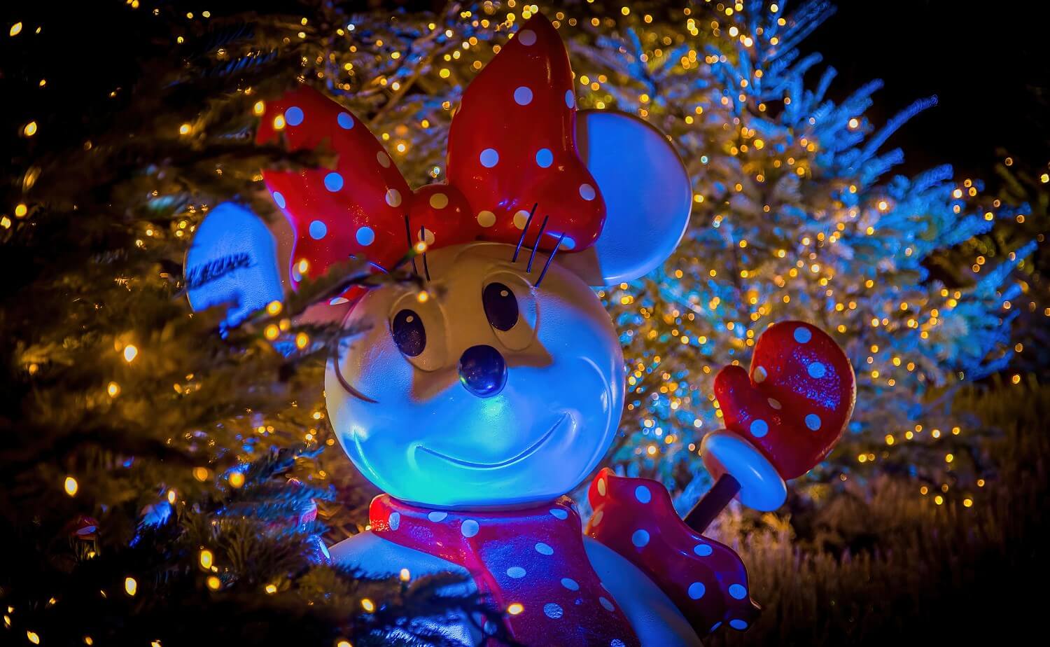 Kopf des Minnie Mouse Schneemannes, eingerahmt von verschneiten Bäumen voller kleiner Lichter