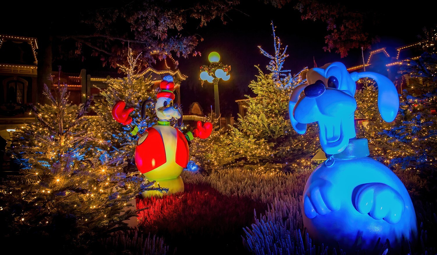 Pluto und Goofy als Schneemänner in einem funkelnden Wäldchen im Disneyland Park