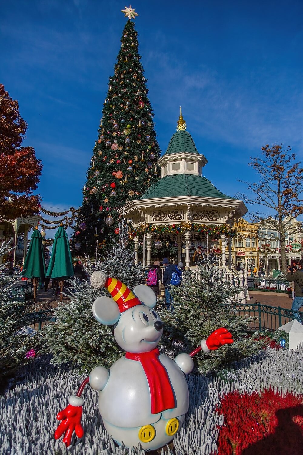 Mickey Mouse Schneemann am Town Square, dahinter der weihnachtlich dekorierte Gazebo und der große Weihnachtsbaum