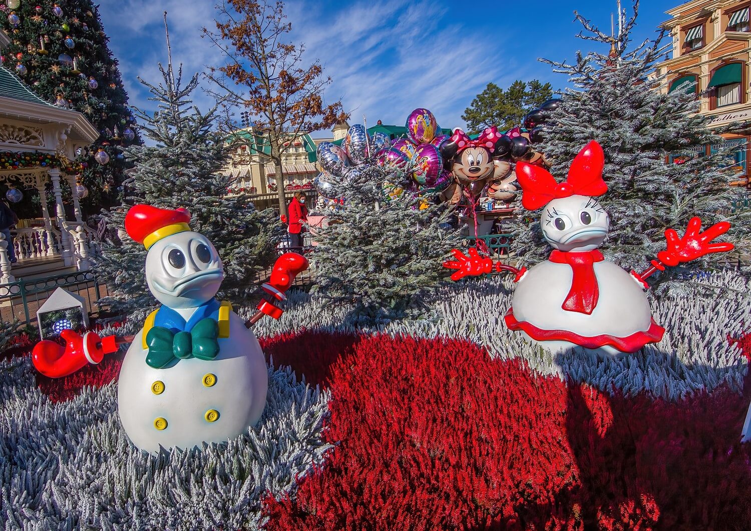 Schneemänner im Look von Donald und Daisy, im Hintergrund schaut ein fröhlicher Minnie Mouse Ballon durch die verschneiten Bäumchen