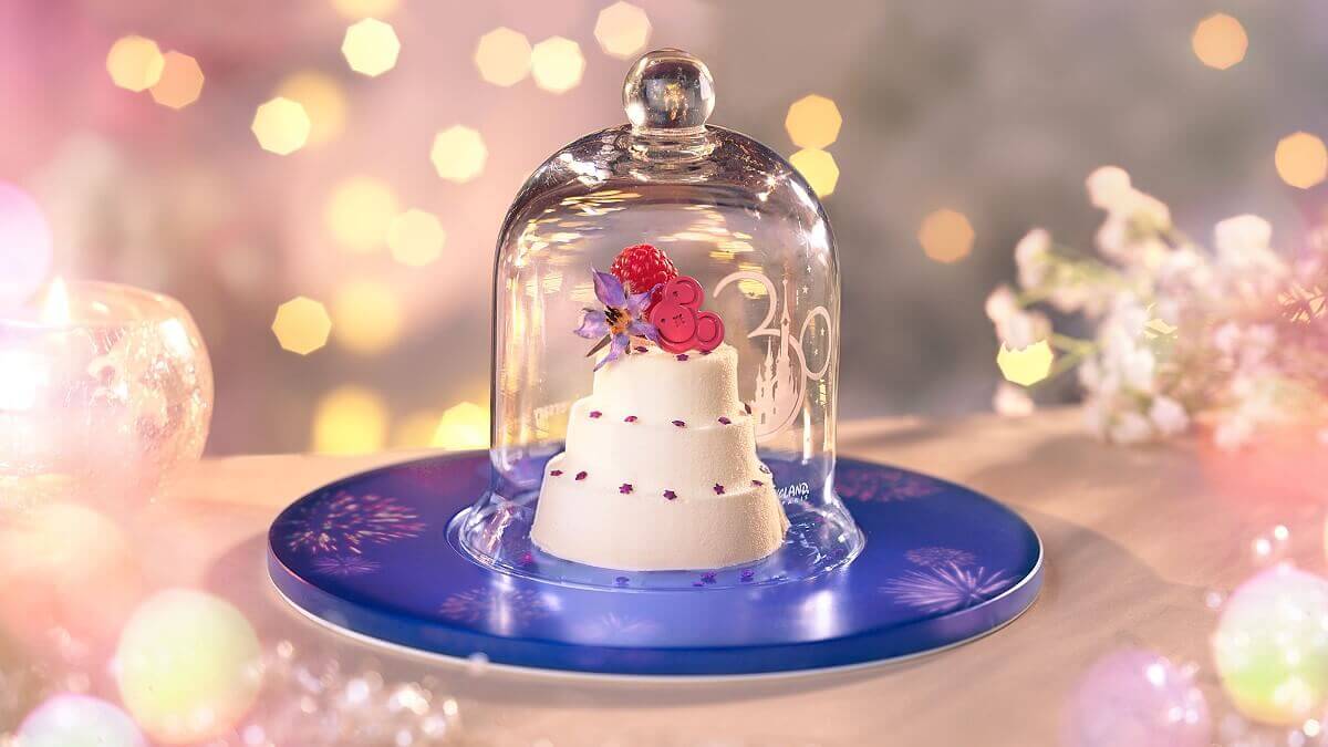 A three-tiered cake under a glass hood, on which a 30 can be seen, stand on a blue plate