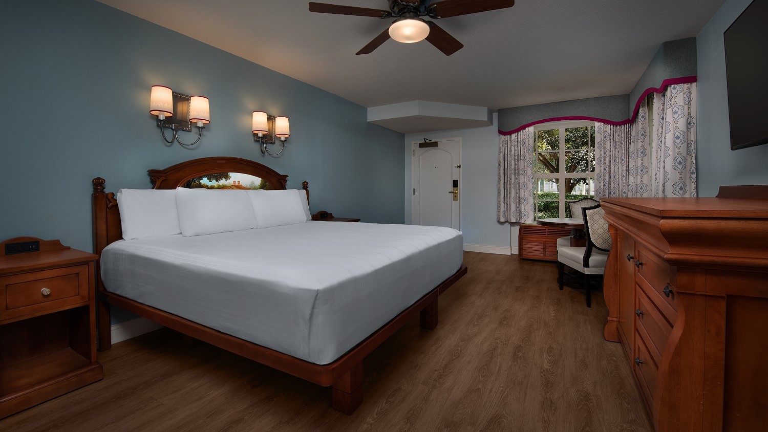 Geräumiges Hotelzimmer mit Kingsizebett, Kommode, Tisch mit Stühlen und Holzboden