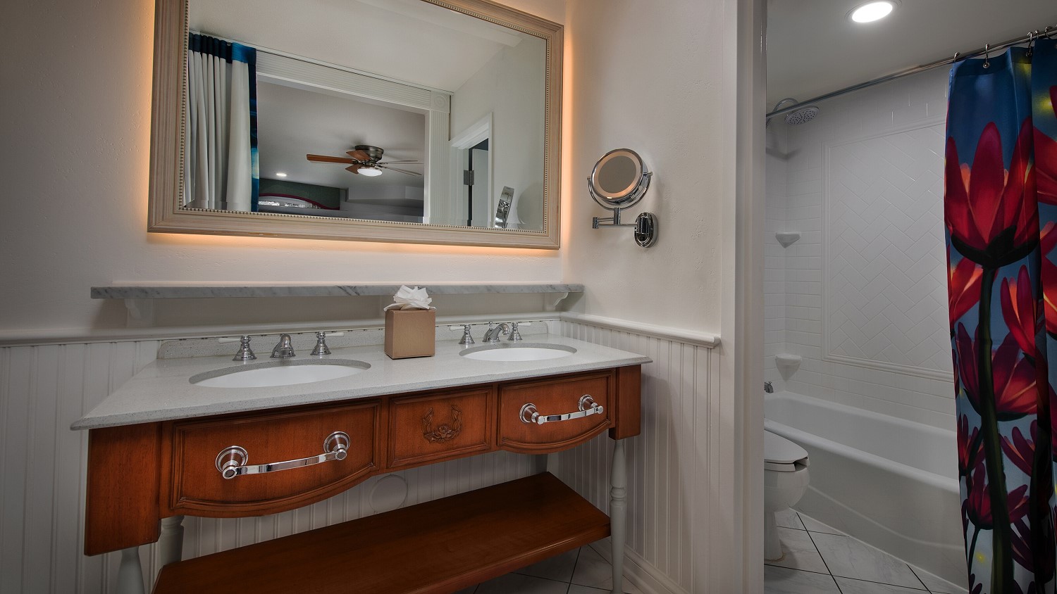 Badezimmer mit zwei Waschbecken und großem Spiegel sowie WC und Duschwanne in Disney's Port Orleans Riverside Resort 